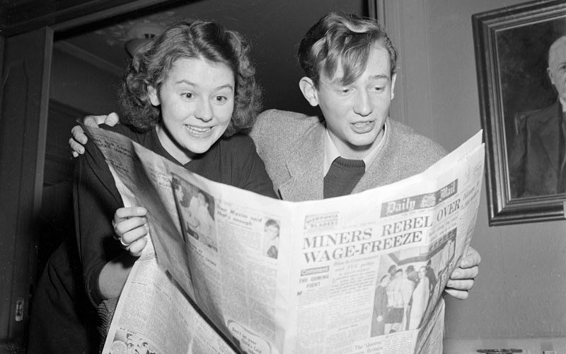Två unga personer på 40-talet som läser en tidning